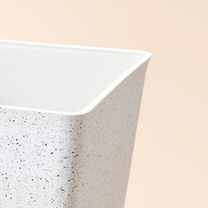 A close-up of the white planter, showing its speckled and plastic features.