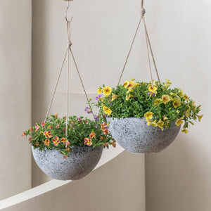 A pair of light gray planters are hung at the corner of the stairs, potted with yellow flowers. 