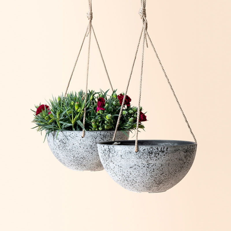 A set of two light gray hanging planters, made from recyclable plastic and natural stone powders.