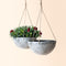A set of two light gray hanging planters, made from recyclable plastic and natural stone powders.