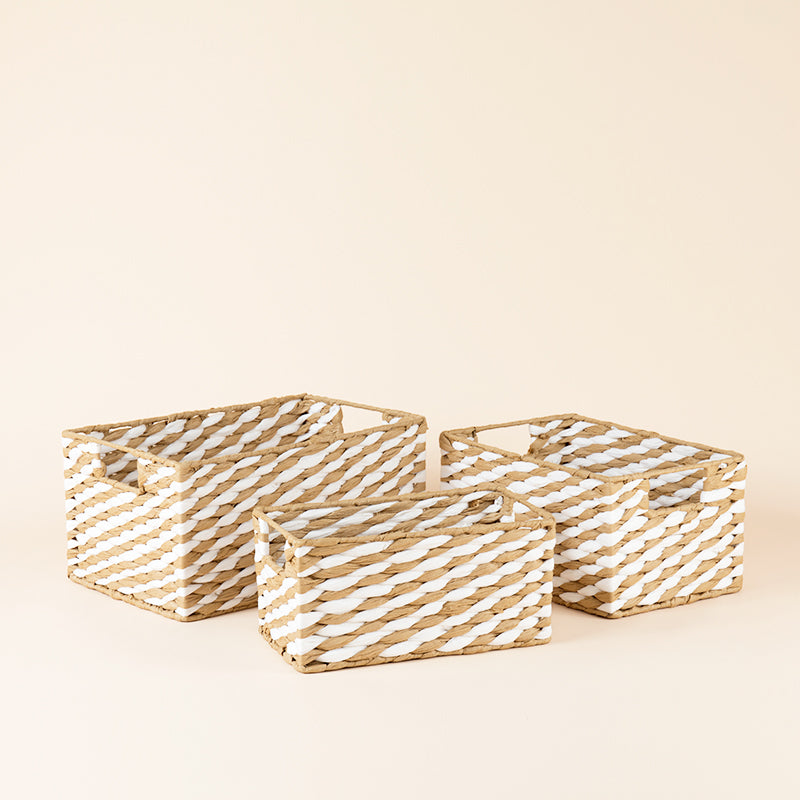 A set of beige paper rope baskets in three sizes. Intersecting lines weave together recycled paper rope and dowel-style handles.