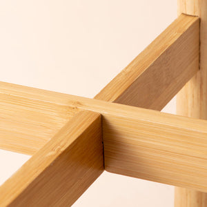A close up of the wooden stand that is used to support the Lorca white and blue pot, built by two crossing pieces.