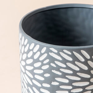 A close-up of the planter,  showing its white daisies embossed pattern and the smooth rim.