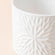 A close-up of the lumen white pot, showing its embossed daisies pattern and its ceramic feature.