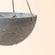 A close up of gray hanging planter, showing its sturdy rope and the plain marble pattern around its exterior.