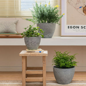 A set of three different-sized pots are displayed in the room, in front of a picture frame.