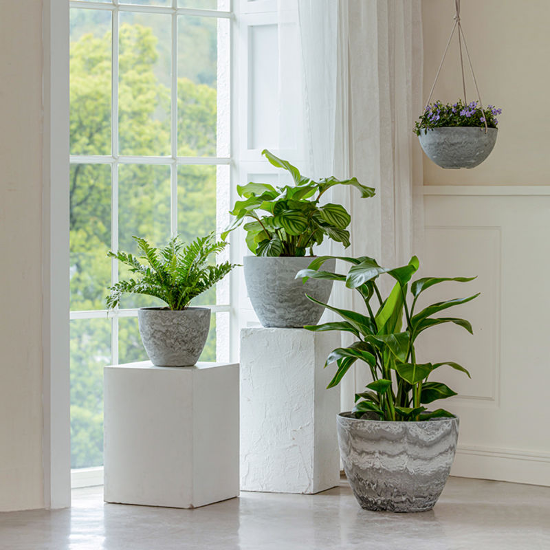 Planters in different sizes are displayed in a staggered way. The hanging grey planters are displayed on the right with flowers in it.