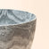 A close-up of the white-grey palette planter, showing its waves pattern design and the smooth curve.