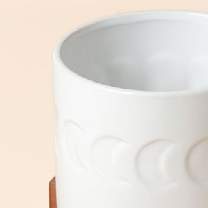 A close view of white ceramic planter, showing its decorative moon patterns.