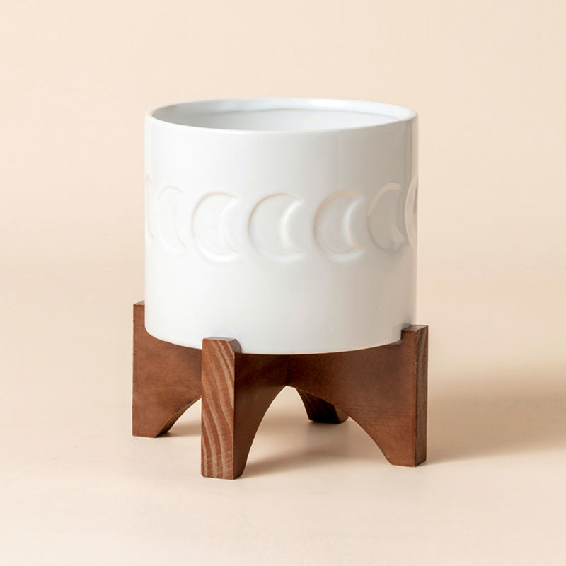 A full view of white planter pot with moon patterns and wooden stand, made of premium ceramic.