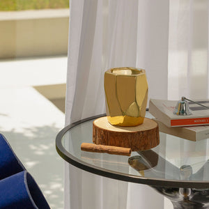 A burning candle is displayed on a glass coffee table by the French windows.