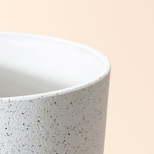 A close-up of the white planter, showing its speckled pattern around the exterior and its pure white design for the inner space.