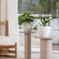 Two 11.3-inch white planters are displayed in front of a chair, each pot is placed on a grey side table.A close-up of the pot, showing its speckled feature and the pure white interior surface.