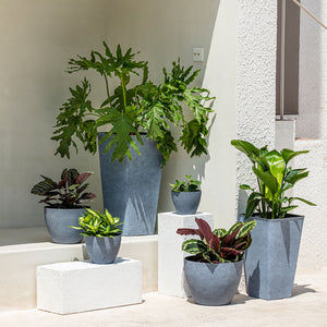 The 8.6-inch rounded gray planter is placed on the ground outside, surrounded by planters of different sizes.