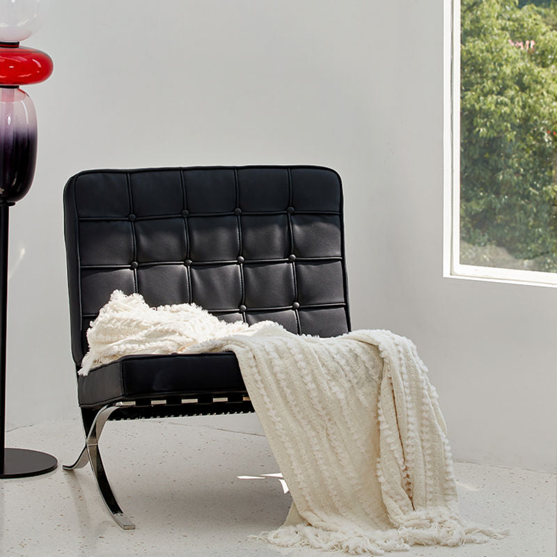 The off-white chenille throw flows freely on the dark couch chair, showing its usage for an afternoon rest.