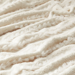 A close-up of the tufted decoration on the off-white chenille throw, which is ultra soft and fluffy.