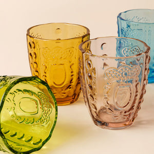 A display of four glasses with the green glass lying down on the side. 