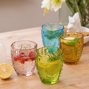 A picture showing the usage of four drinking glasses, containing  flower and fruit pieces.