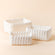 A set of three storage baskets made of pure white paper ropes, placed in a staggered way.