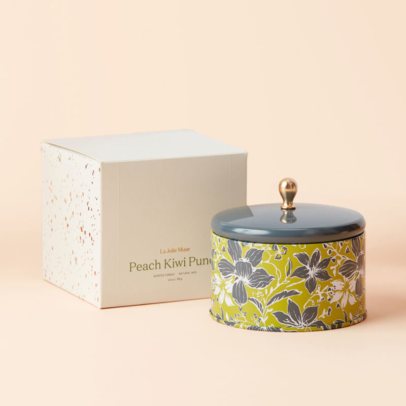 A jar of Peach and Kiwi Scented candle with its white packing box.