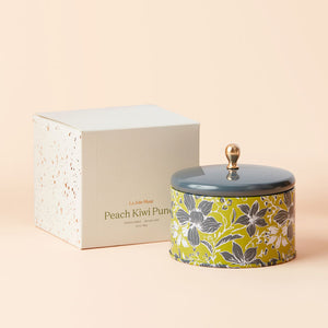 A jar of Peach and Kiwi Scented candle with its white packing box.