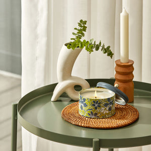 A jar of burning candle is placed on a green coffee table by the French windows.