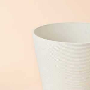 A close-up of the white planter, showing its spiral lines design and the taper shaped.