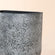 A close up of gray wall planter, showing its concrete texture and semicircular opening. 