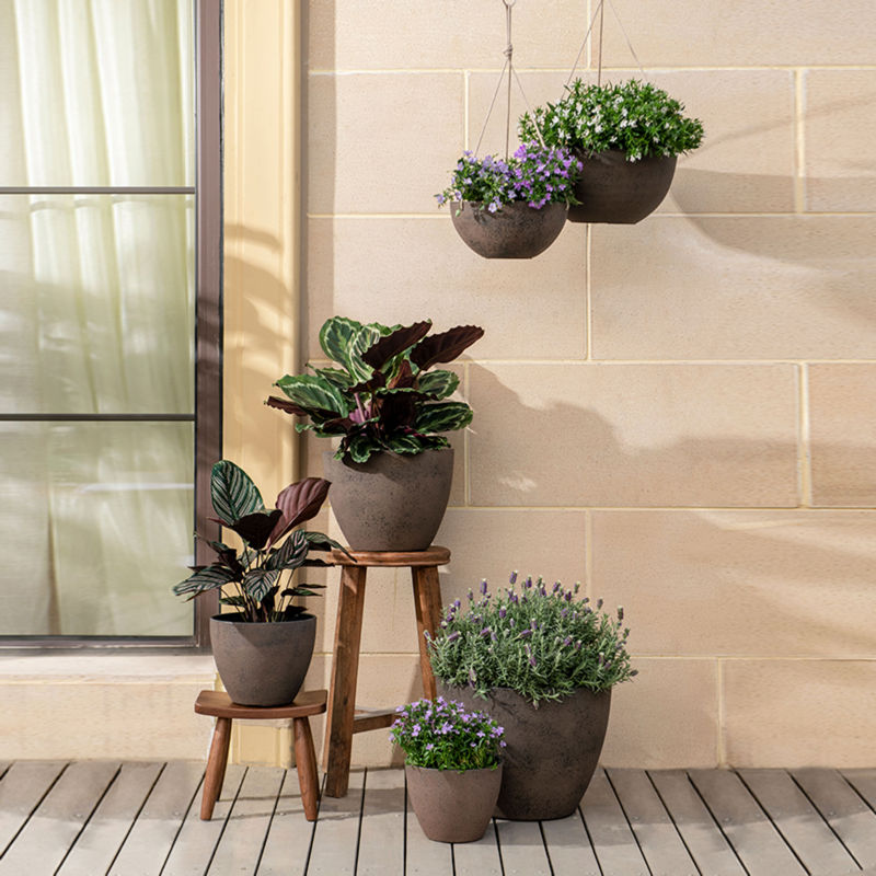 Six rusty planters in different sizes and shapes are displayed in front of a beige wall, including two outdoor planters.