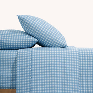 Paulina Blue Check Picot Edge 200 count cotton sheet set. White and blue gingham pillows and white and blue gingham sheets on bed from side view.'