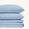 Paulina Blue Check Picot Edge 200 thread count cotton bed sheet set. Two white and blue gingham pillows stacked on folded white and blue gingham sheet set.