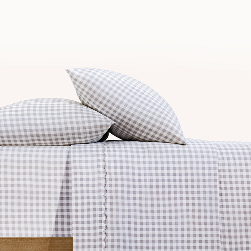 Paulina Pewter Check Picot Edge 200 count cotton sheet set. White and gray gingham pillows and white and gray gingham sheets on bed from side view.