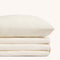 Camille Ivory Lace bed sheet set. Single ivory pillow stacked on folded ivory sheet set.