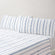 Camille Blue Stripe bed set. Blue and white dotted pillows and blue and white sheets on bed from side angle.