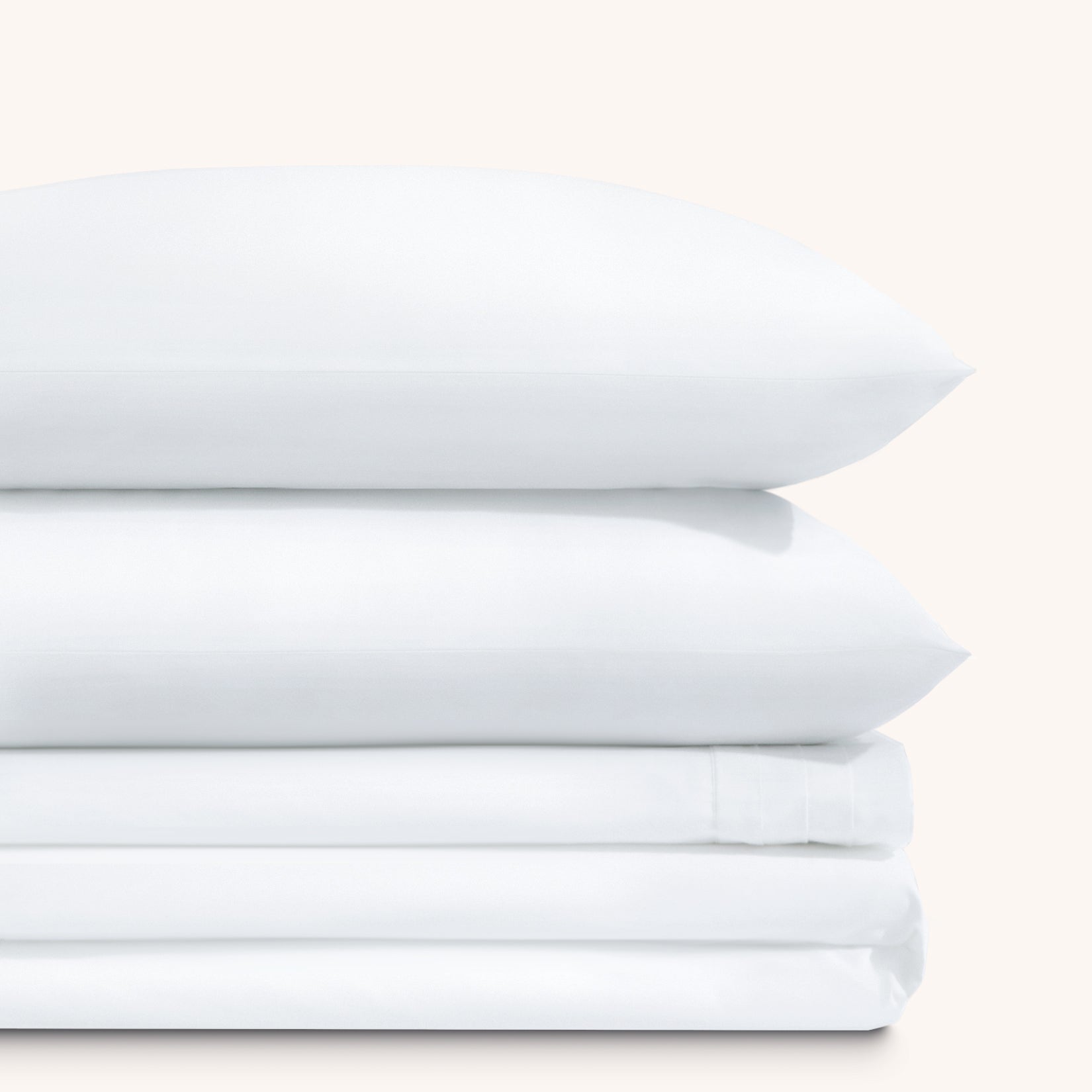 Camille Classic White Pleated bed sheet set. Two white pillows stacked on folded white sheet set.