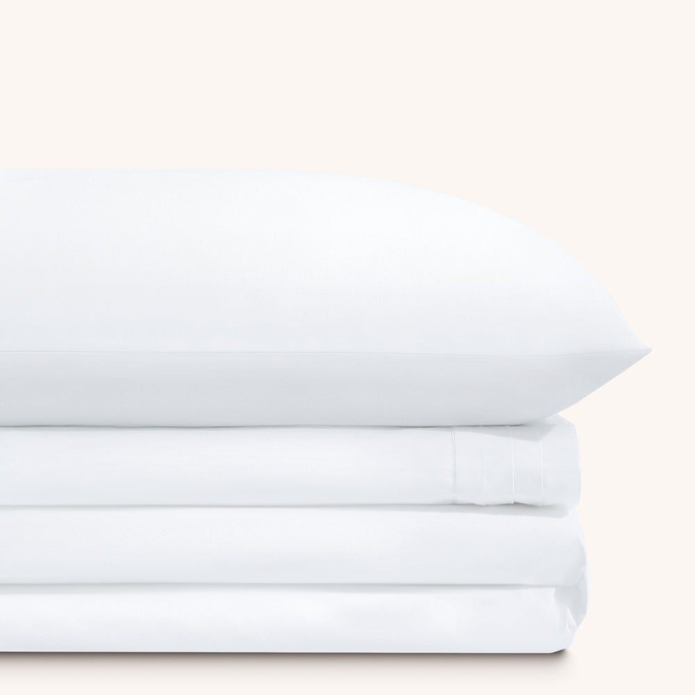 Camille Classic White Pleated bed sheet set. Single white pillow stacked on folded white sheet set.