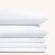 Camille Classic White Pleated bed sheet set. Two white pillows stacked on folded white sheet set.
