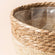 A close up of seagrass planter, showing its woven texture and dual-color stitching.