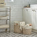 Two baskets in different sizes are placed on the tile floor, between a trolley and a white cabinet. 