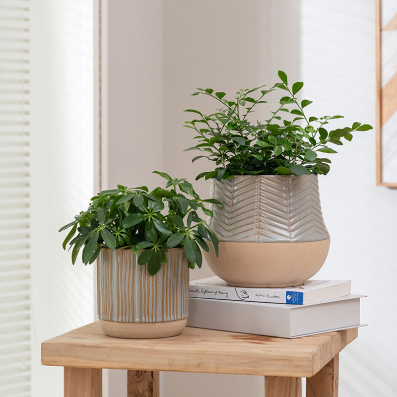 A pair of gray and beige pots are placed on a wooden square table with two books.