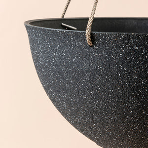A close up of speckled black hanging pots, showing its textured exterior and sturdy hanging rope.