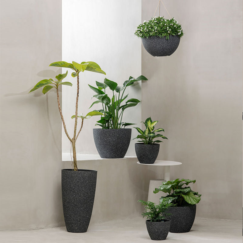 A series of black planters are displayed in a staggered way. The set of black pots with white speckled is at the center, on the grey step.