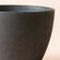 Close-up detail of the black planter, showing its white speckled and smooth curve.