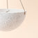 A close up of white hanging pots with speckles, showing its sturdy rope and bowl shape design.