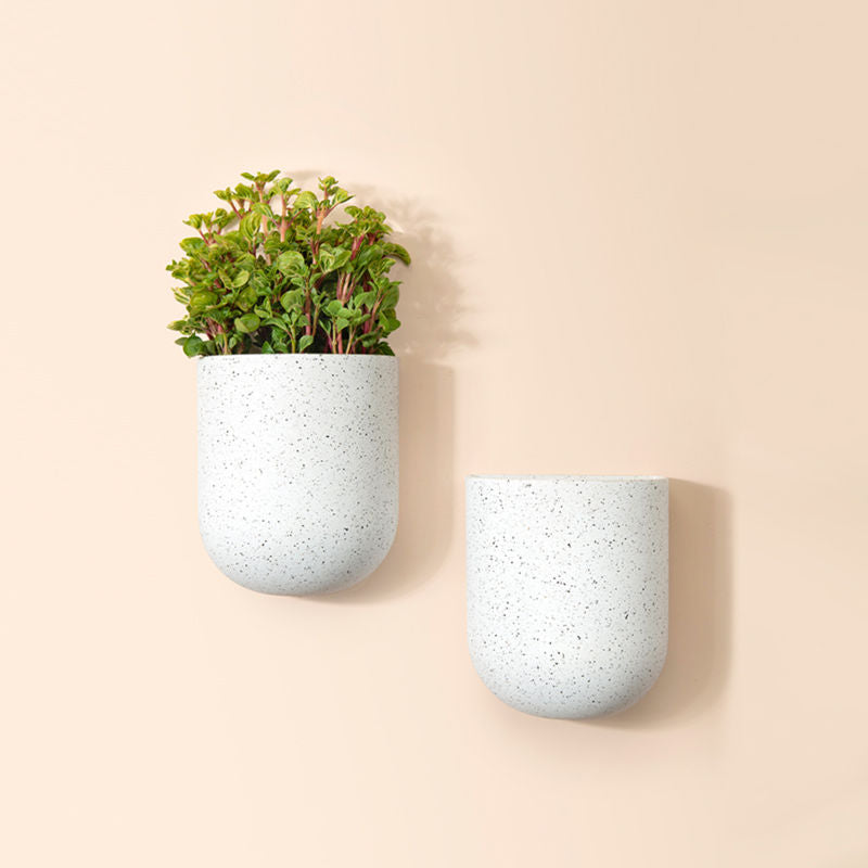 A set of two small wall planters in speckled white, made from recyclable plastic and natural stone powders.