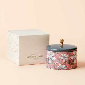 A jar of Sunkissed Rose candle with its white packing box.