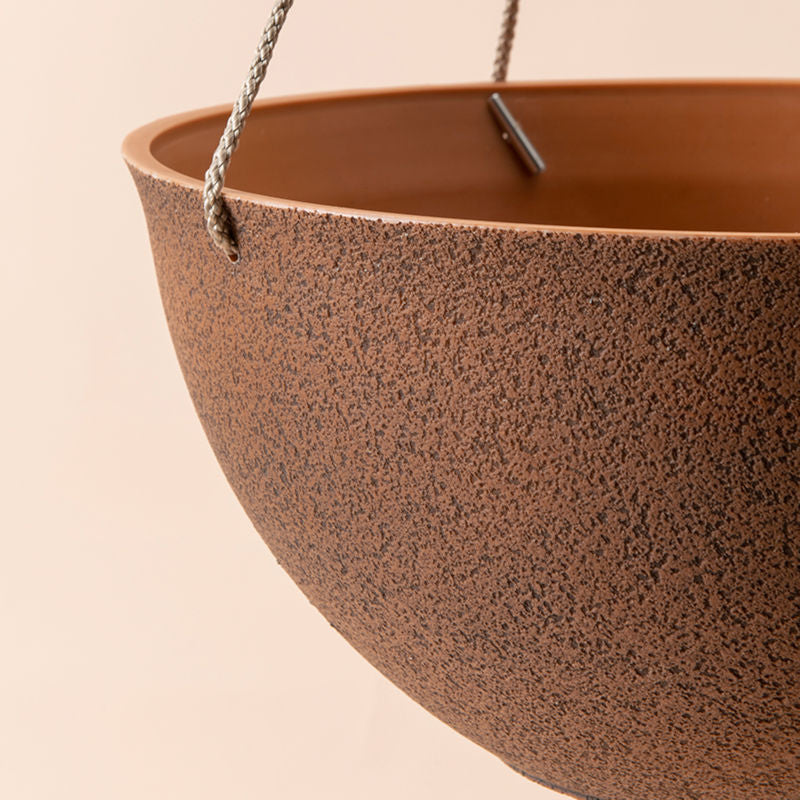A close up of terracotta hanging pot, showing its earthy color and sturdy rope.