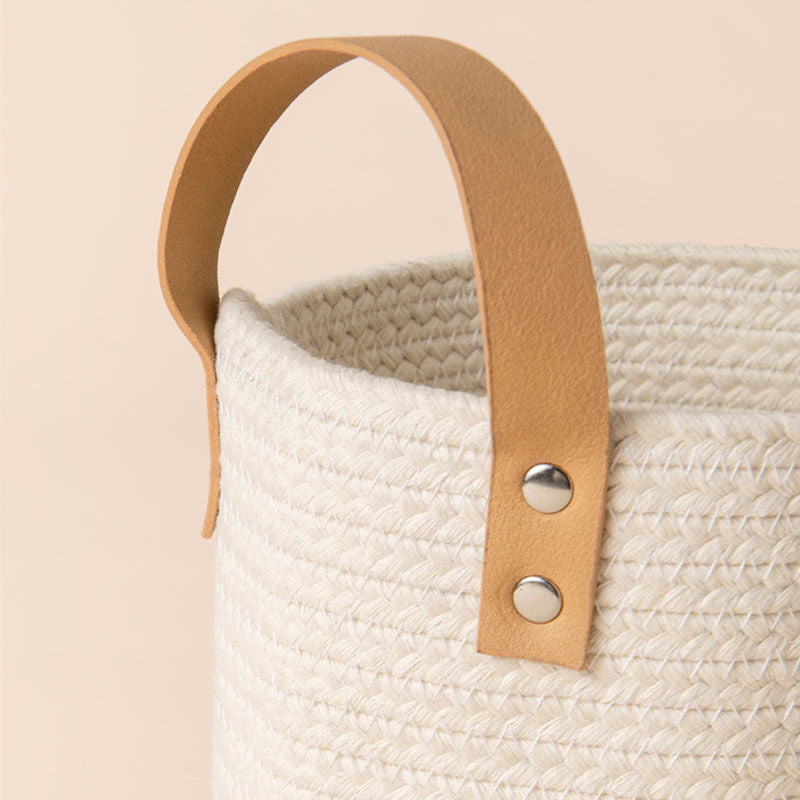 A close up of tote beige basket, showing its cotton texture and leather handle.