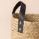 A close up of tote water hyacinth basket, showing its leather handle and woven pattern.