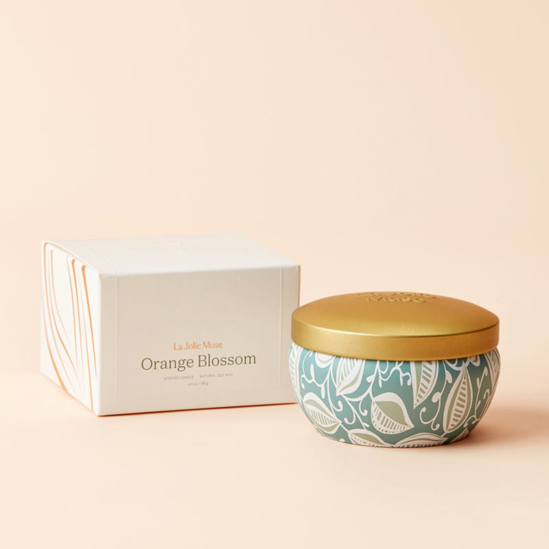 A tin of Orange and Blossom candle with its white packing box.